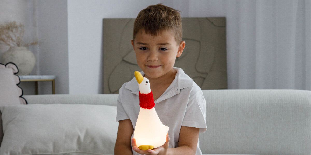 Lampka nocna INNOGIO GIOduck Kaczka GIO-145, dotyk, reagowanie, dostosowanie, nastrój, dziecko trzyma w rękach lampkę i się uśmiecha