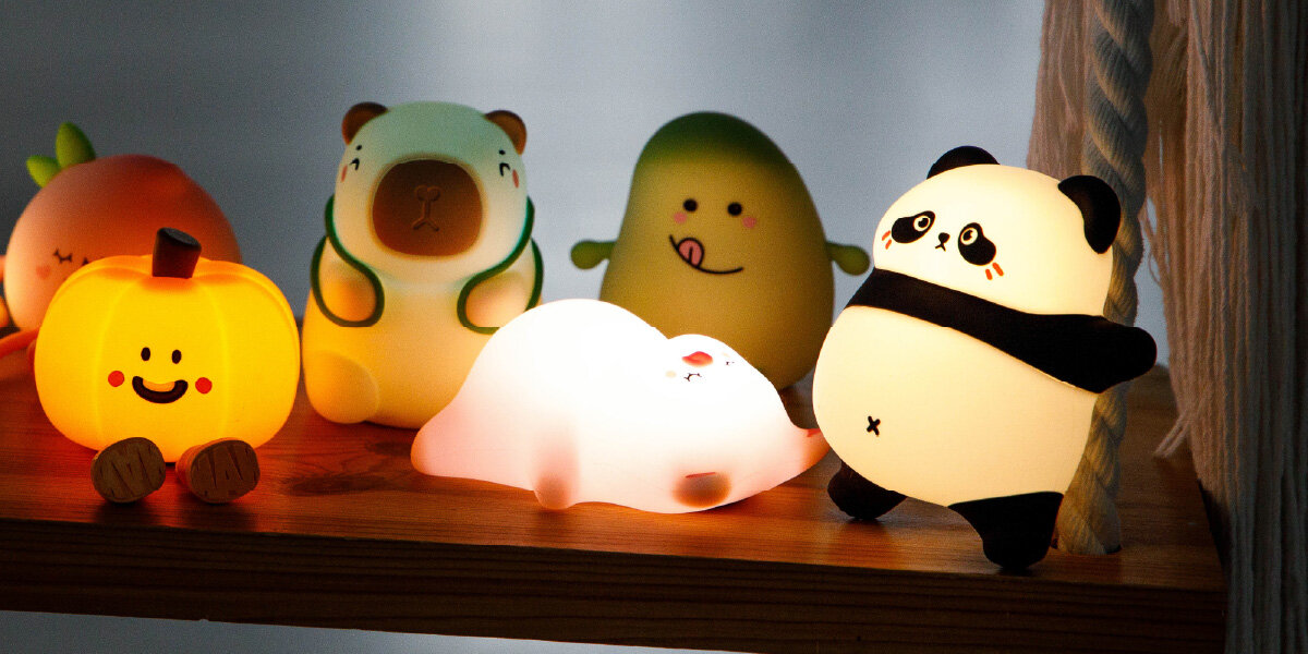Lampka nocna INNOGIO GIOcapybara Kapibara GIO-154, silikon, miękkie, bezpieczna, kształt, na półce leżą różnego rodzaju lampki nocne w tym kapibara
