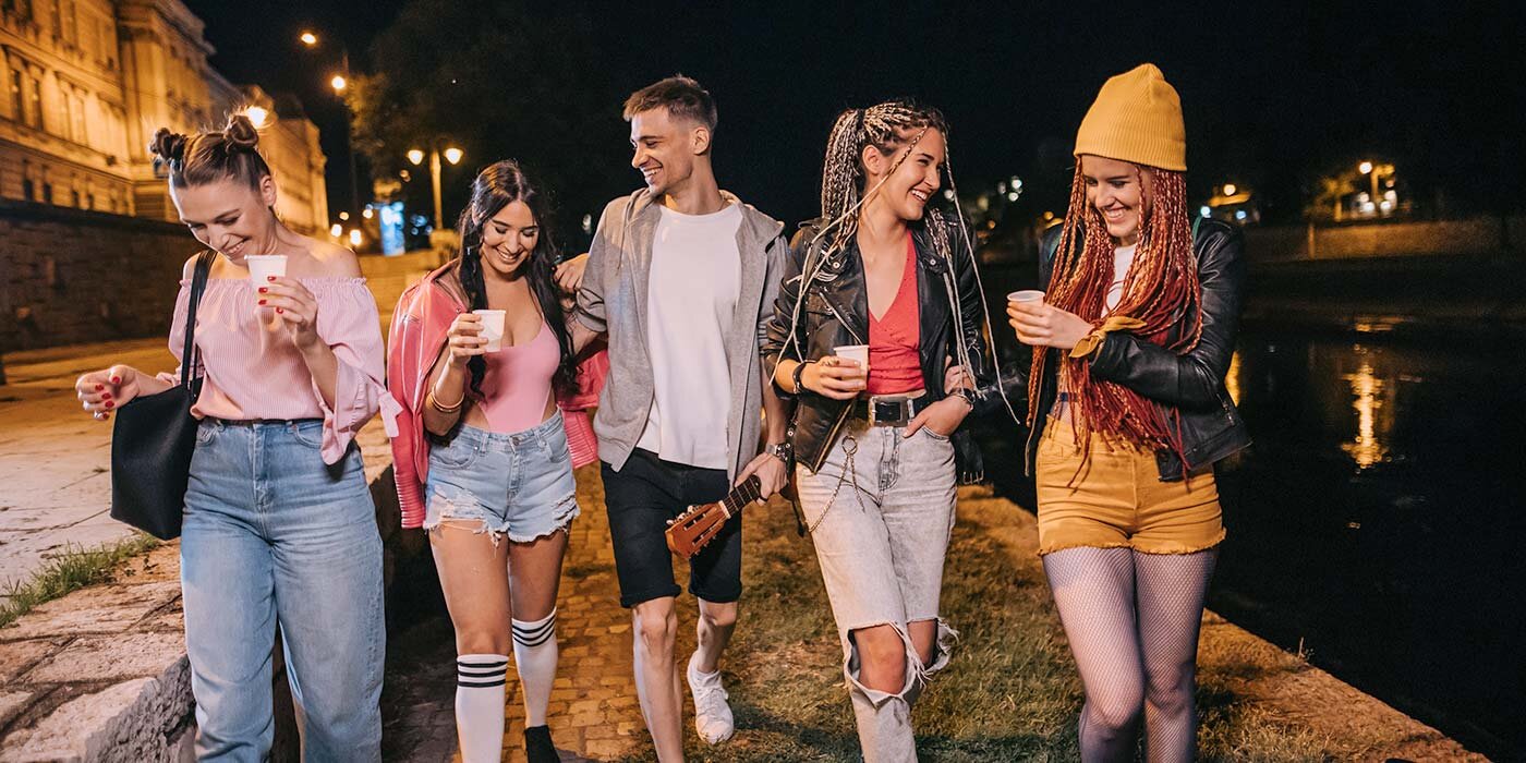 Pięcioro przyjaciół, cztery kobiety i jeden mężczyzna, spaceruje nocą wzdłuż rzeki, trzymając drinki pod latarniami. Pionowy suwak dzieli obraz, lewa strona jest przyciemniona i stonowana, a prawa jasna i kolorowa, odsłaniając wyraźniejsze detale, takie jak żółta czapka, podarte dżinsy i odbicia w wodzie. Pięcioro przyjaciół, cztery kobiety i jeden mężczyzna, spaceruje nocą wzdłuż rzeki, trzymając drinki pod latarniami. Pionowy suwak dzieli obraz, lewa strona jest przyciemniona i stonowana, a prawa jasna i kolorowa, odsłaniając wyraźniejsze detale, takie jak żółta czapka, podarte dżinsy i odbicia w wodzie.