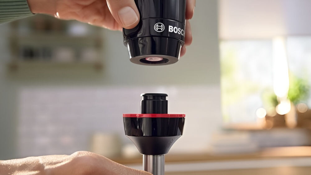 Blender BOSCH ErgoMixx MS61B6150 osoba trzyma czarny blender i końcówkę składa oba elementy ze sobą łatwość obsługi jedno kliknięcie odłączenie stopy miksującej komfort oszczędność czasu