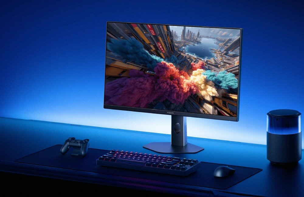 Monitor XIAOMI G27i Monitor stojący na biurku obok klawiatury i myszki wyświetlający kolorowe dymy nad futurystycznym miastem, czas reakcji, redukcja smużenia
