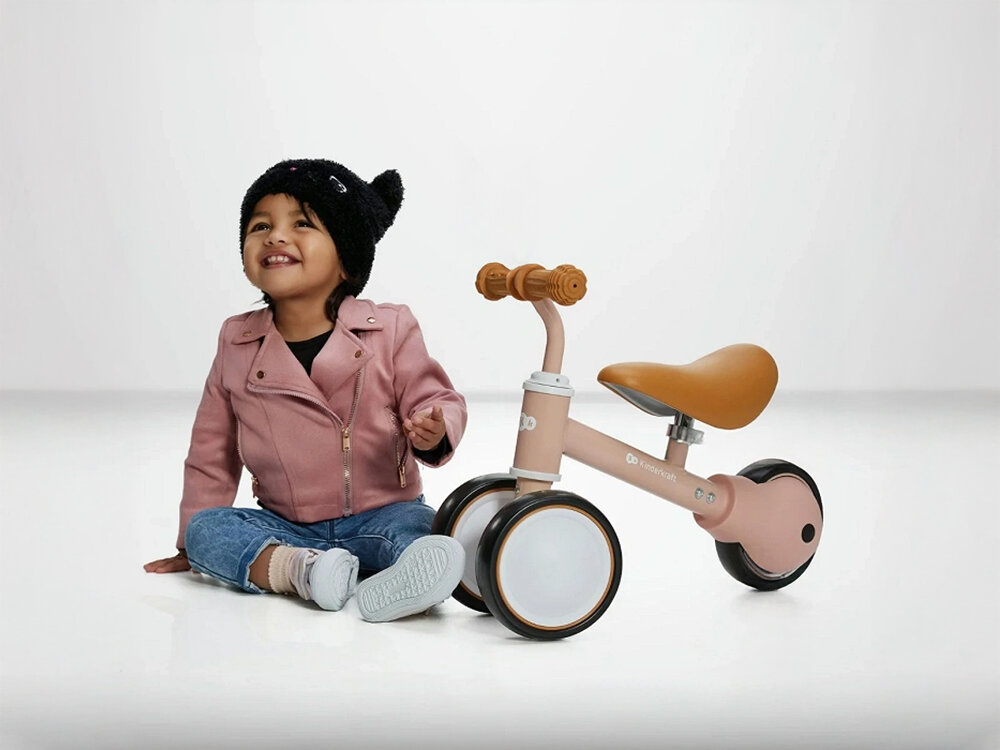 Kinderkraft rowerek biegowy CUTIE PINK pierwsza jazda różowy rowerek siodełko gumowe uchwyty czarno białe koła obok siedzi maluch