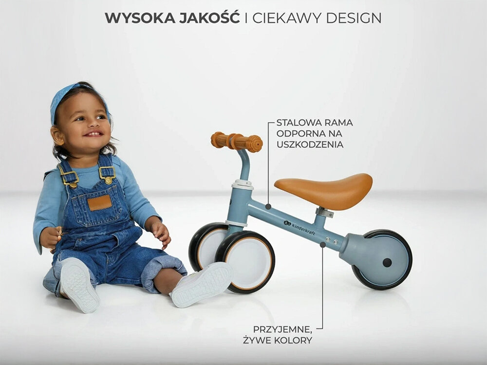 Kinderkraft rowerek biegowy CUTIE PINK białe tło dziecko siedzi obok niebieskiego rowerka strzałki kółka siodełko funkcjonalność estetyka 50 x 22 x 37 cm lekka konstrukcja o wadze 1,8 kg poręczny wygodny w użytkowaniu rozwój równowagi koordynacji bezpieczna budowa pastelowa kolorystyka Solidne wykonanie (metalowa rama) trwałość przemyślane rozwiązania codzienne spacery i zabawy