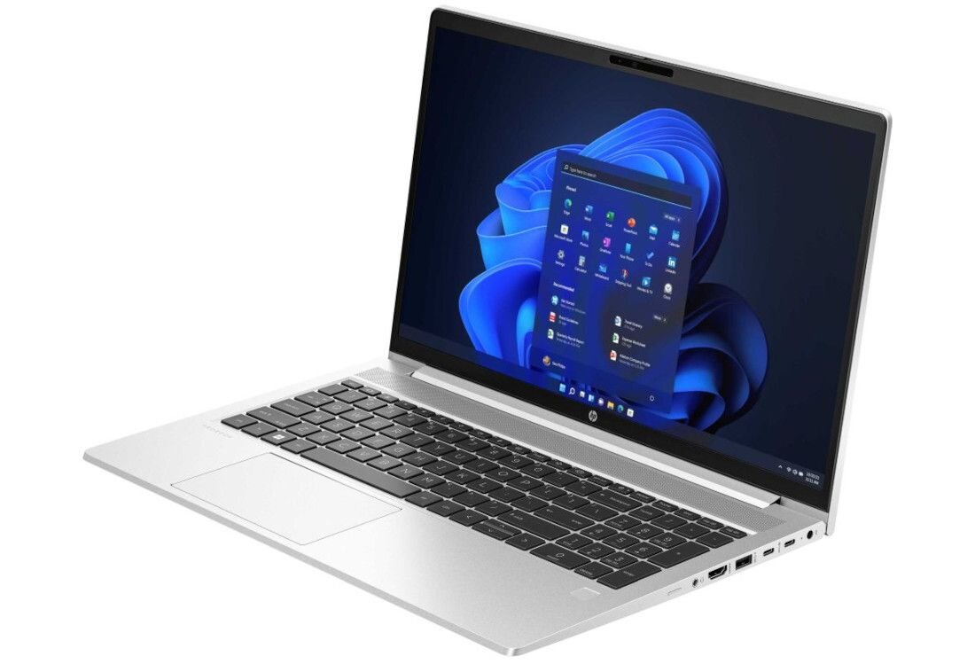 Laptop HP ProBook 450 G10 w srebrnej obudowie, widok pod kątem z otwartym ekranem prezentującym interfejs Windows 11 z menu Start i dynamiczną, abstrakcyjną tapetą w odcieniach niebieskiego, z widocznym portem Ethernet i USB. - RAM DDR4, dysk SSD 