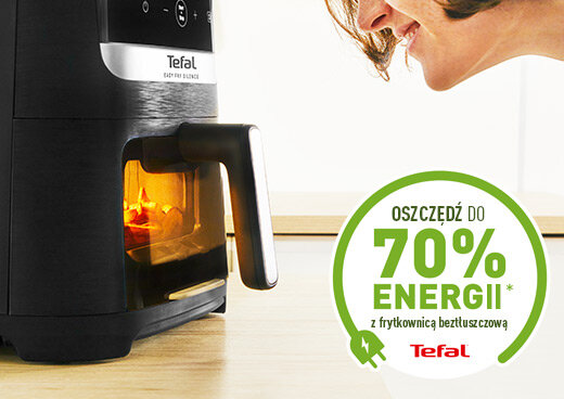 Na blacie stoi czarna frytkownica beztłuszczowa z okienkiem, przez które widać wnętrze urządzenia. Obok znajduje się napis: \'Oszczędź do 70% energii* z frytkownicą beztłuszczową\' oraz logo Tefal.
