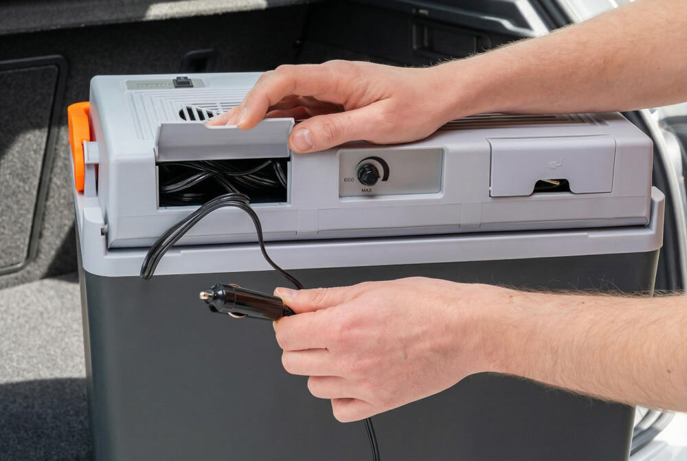 Lodówka turystyczna GÖTZE & JENSEN TC810G Zbliżenie na tylny panel lodówki turystycznej Götze & Jensen z wyciągniętym kablem zasilającym do gniazda zapalniczki samochodowej 12V.