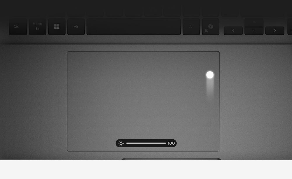 Laptop ASUS VivoBook z dużym touchpadem pokazuje suwak jasności na panelu dotykowym podczas codziennej pracy biurowej