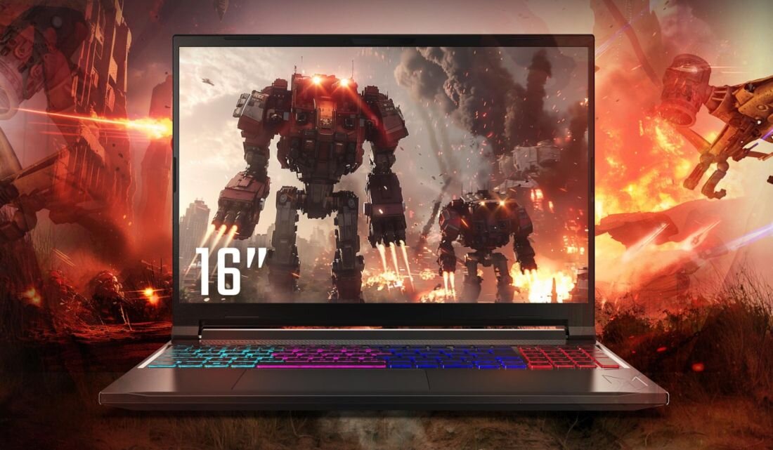 Laptop z kolorową klawiaturą wyświetla na ekranie grafikę przedstawiającą roboty w scenerii bitewnej. Na ekranie widoczny jest napis.