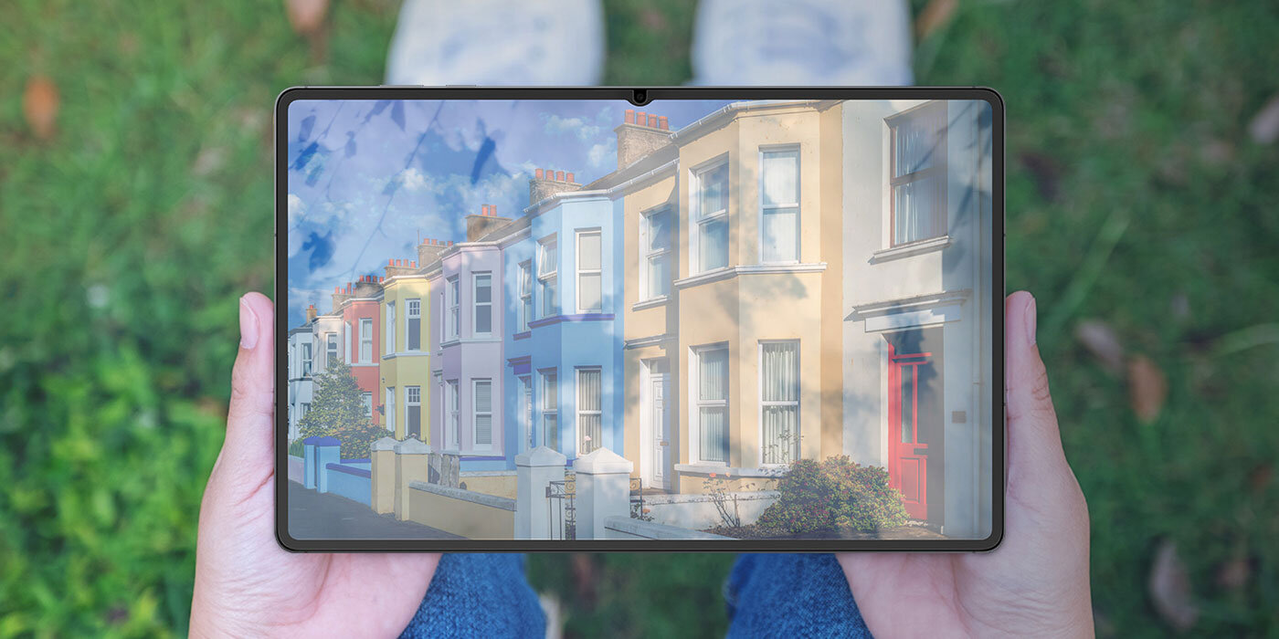 Osoba siedząca na trawie trzyma Galaxy Tab S11 Ultra na kolanach. Światło słoneczne odbija się od ekranu bez powłoki antyrefleksyjnej, przez co trudno dostrzec zawartość ekranu.