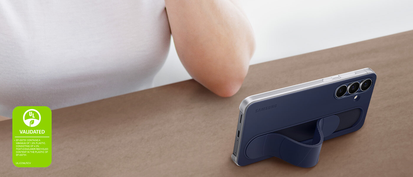 Galaxy S25 FE w etui Standing Grip w kolorze ciemnoniebieskim stoi poziomo pod kątem na stole. Telefon jest używany przez osobę do oglądania. W rogu zdjęcia znajduje się znak walidacji ekologicznej UL z napisem: „EF-GS731 ZAWIERA MINIMUM 1,9% PLASTIKU, SKŁADAJĄC SIĘ Z 4,3% ZAWARTOŚCI PO RECYKLINGU W PLASTIKU EF-GS731. UL.COM/ECV”. Galaxy S25 FE w etui Standing Grip w kolorze ciemnoniebieskim stoi poziomo pod kątem na stole. Telefon jest używany przez osobę do oglądania. W rogu zdjęcia znajduje się znak walidacji ekologicznej UL z napisem: „EF-GS731 ZAWIERA MINIMUM 1,9% PLASTIKU, SKŁADAJĄC SIĘ Z 4,3% ZAWARTOŚCI PO RECYKLINGU W PLASTIKU EF-GS731. UL.COM/ECV”.