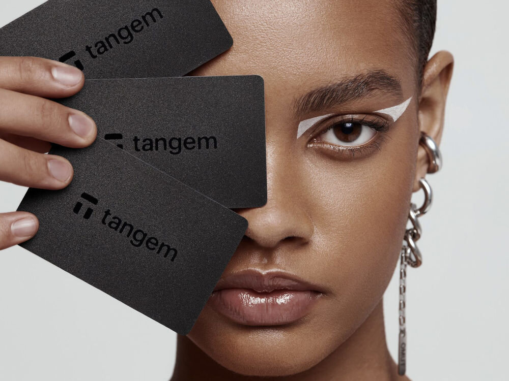 Portfel kryptowalut TANGEM 3 Card Set Osoba trzymająca trzy czarne karty Tangem przy twarzy, ukazujące ich minimalistyczny design