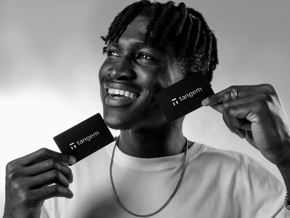 Portfel kryptowalut TANGEM 2 Card Set Osoba trzymająca dwie czarne karty Tangem przy twarzy, ukazujące ich minimalistyczny design