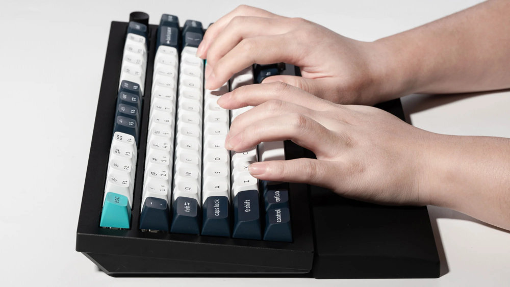 Keychron Silicone Palm Rest wspiera prawidłową pozycję nadgarstków zmniejsza ryzyko wystąpienia urazów - podkładka przy klawiaturze na białym tle, widać dłonie