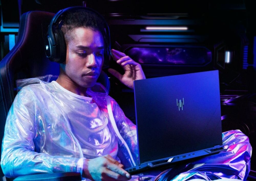  Gamer mężczyzna w słuchawkach futurystycznej kurtce holograficznej gra na laptopie Predator granatowym w fotelu, neony fioletowe niebieskie w tle, setup gaming - Bateria 90 Wh 