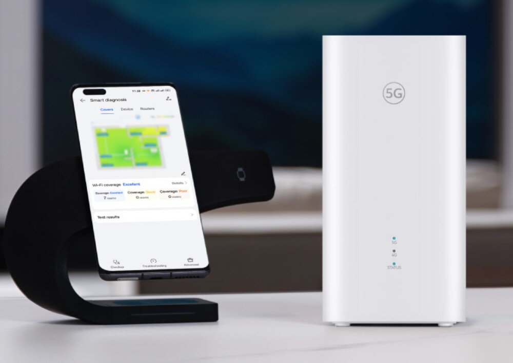 Router HUAWEI Zowee 5G router obok smartfona umieszczonego na podstawce, na którego ekranie widoczna jest aplikacja do diagnostyki zasięgu Wi-Fi w mieszkaniu