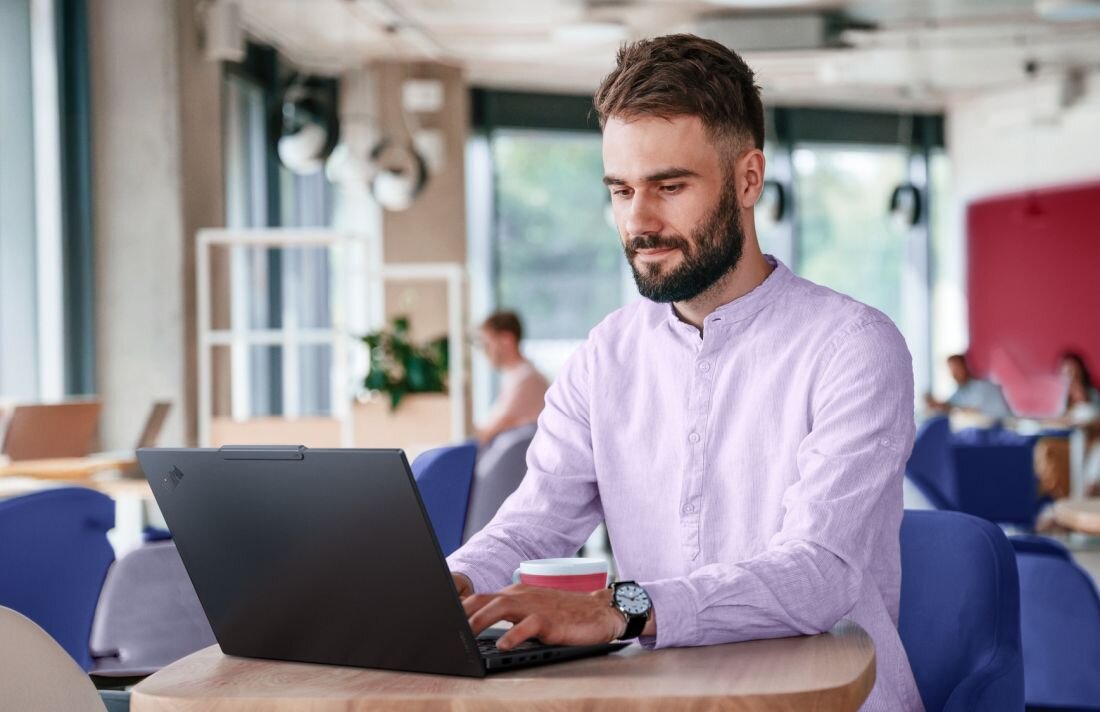 Osoba pracuje na laptopie Lenovo ThinkPad z pamięcią LPDDR5x przy stoliku w nowoczesnej przestrzeni co-workingowej - Pamięć LPDDR5x 8533 MHz   