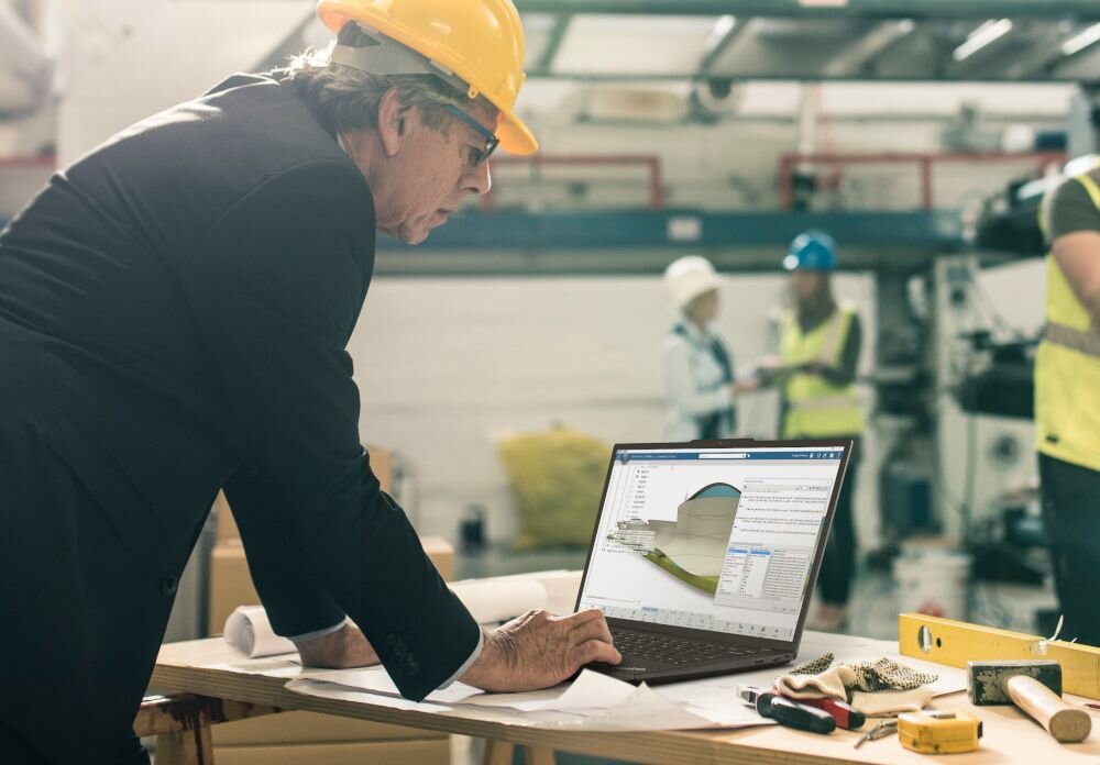 Inżynier w kasku używa laptopa Lenovo ThinkPad z procesorem Intel Core na placu budowy przemysłowej. - mobilność z mocą profesjonalnej stacji roboczej 