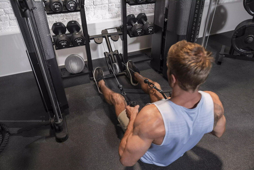 Brama do ćwiczeń INSPIRE FITNESS FT2 PRO + Ławka FID7.1 pomieszczenie siłownia brama na tle ceglanej ściany osoba ćwiczy ramiona regulowany drążek multi-grip wiele możliwości chwytu dopasowanie ćwiczeń do własnych umiejętności uchwyty wspinaczkowe wzmacniać mięśnie grzbietu i rąk