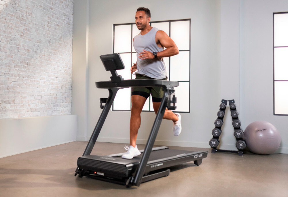 Bieżnia elektryczna CENTR RunR-S 2238W 16km-h pomieszczenie bieżnia na środku pomieszczenia osoba biegnie na bieżni w tle okno ściana z cegły regulacja prędkości od 0,8 do 16 km/h dopasowanie intensywności ćwiczeń do indywidualnych potrzeb silnik bezszczotkowy o mocy 1,5 HP (ciągły) i mocy szczytowej 3,0 HP płynna i stabilna praca