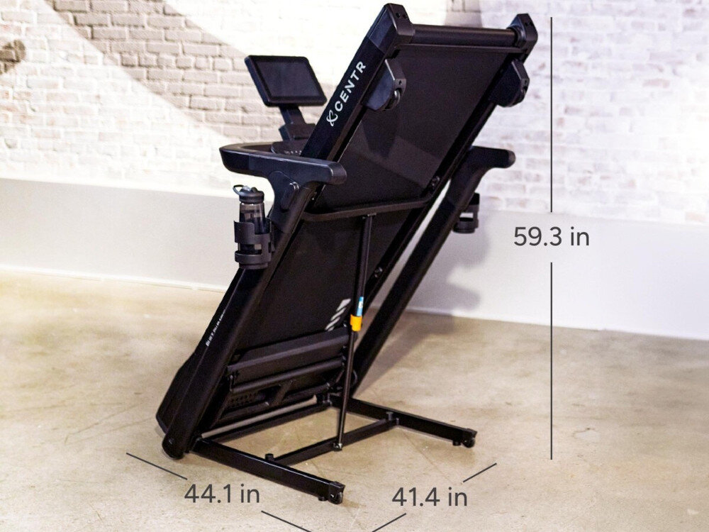 Bieżnia elektryczna CENTR RunR-S 2238W 16km-h pomieszczenie złożona bieżnia na środku pomieszczenia wokół strzałki wyznaczające wymiary mechanizm składania bez użycia narzędzi 108.5 × 108 × 152.8 cm porządek