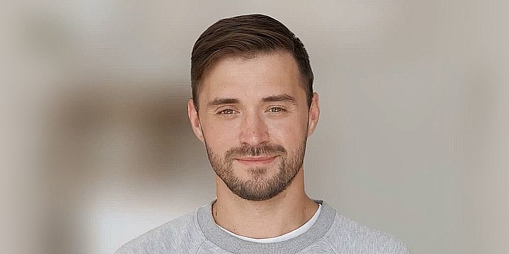 Mężczyzna w szarej bluzie na neutralnym tle – ilustracja zastosowania kamery ASUS AI w laptopach Zenbook 14.