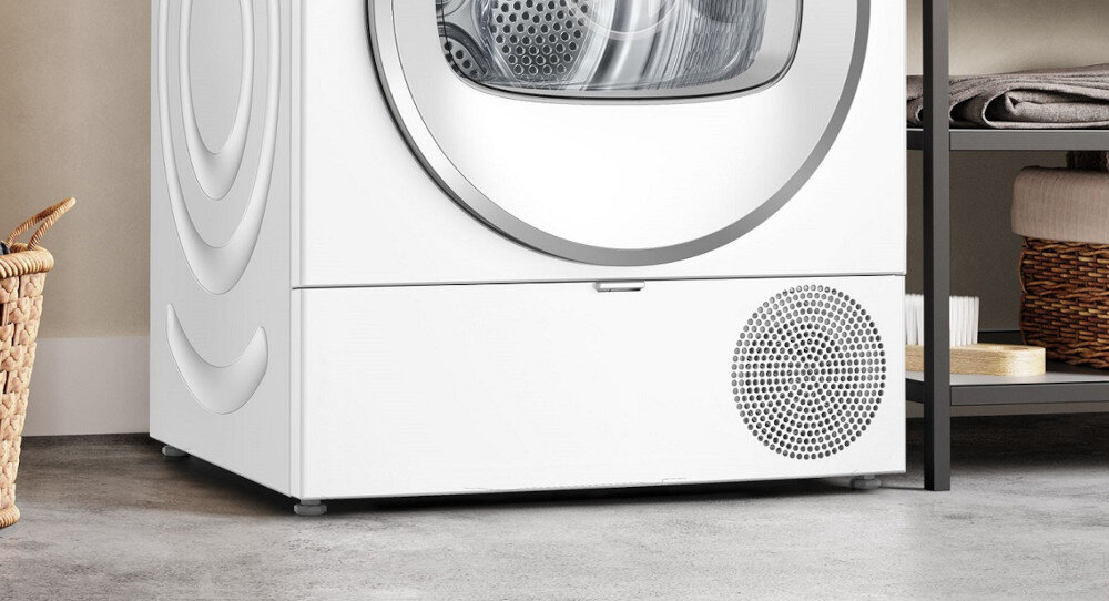 SUSZARKA BOSCH WTH85V9SPL Na zdjęciu pokazany jest dolny front suszarki bębnowej. Widać zamkniętą klapkę serwisową, za którą zazwyczaj znajduje się filtr oraz pojemnik na wodę skroploną. Po prawej stronie jest kratka wentylacyjna, przez którą odbywa się cyrkulacja powietrza w urządzeniu. Całość utrzymana jest w jasnym kolorze, charakterystycznym dla suszarek efektywność energetyczna suszarki czyszczenie filtrów easyclean konserwacja oszczędna praca niezawodne suszenie pielęgnacja filtrów przepływ powietrza w suszarce