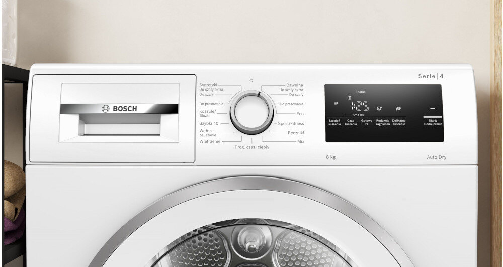 SUSZARKA BOSCH WTH85V9SPL Na zdjęciu jest panel sterowania suszarki: podajnik na środki, pokrętło wyboru programów (np. koszule, bawełna, syntetyki, ręczniki) i elektroniczny wyświetlacz z dodatkowymi opcjami. Całość wygląda estetycznie i funkcjonalnie Wyświetlacz panel sterowanie funkcje programy