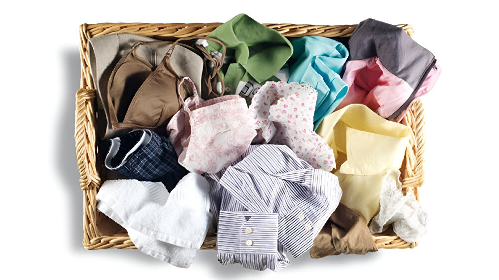 SUSZARKA BOSCH WQG243MSPL Na zdjęciu widoczny jest wiklinowy kosz wypełniony różnorodną odzieżą. W koszu znajdują się m.in. koszule, bielizna, ubrania dziecięce i kolorowe tkaniny. Całość wygląda jak wyjęta po sortowaniu prania lub przygotowana do umieszczenia w pralce. Ubrania są w różnych kolorach i wzorach system suszenia z czujnikami automatyczne suszenie ochrona tkanin wilgotności czujniki temperatury precyzyjne suszenie bez przesuszenia miękkie pranie