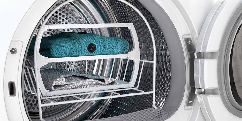 SUSZARKA BOSCH WQG243MSPL Na zdjęciu widać wnętrze suszarki bębnowej z zamontowanym specjalnym stojakiem do suszenia delikatnych rzeczy. Na stojaku leżą sweter oraz inne tkaniny, które wymagają suszenia na płasko, bez obracania w bębnie. Taki sposób suszenia chroni ubrania przed deformacją i rozciąganiem kosz do delikatnego suszenia bez obrotów delikatne tkaniny wełna aksamit pluszowe zabawki butów równomierne ochrona włókien bez ryzyka uszkodzeń ciche