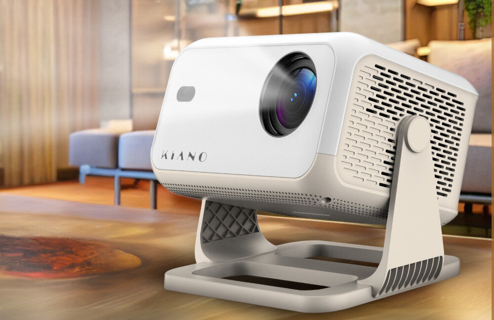 Projektor KIANO Chill kompaktowy rozmiar mobilny do przenoszenia, projektor stojący na drewnianym podłożu w salonie