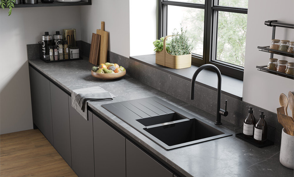 ZLEWOZMYWAK HANSGROHE Z OCIEKACZEM S52 43357290 Kuchnia z długim, ciemnym blatem i czarnym zlewem z ociekaczem oraz baterią przy oknie. Na blacie znajdują się dodatki, takie jak deski, przyprawy i misa z owocami, podkreślające funkcjonalność przestrzeni