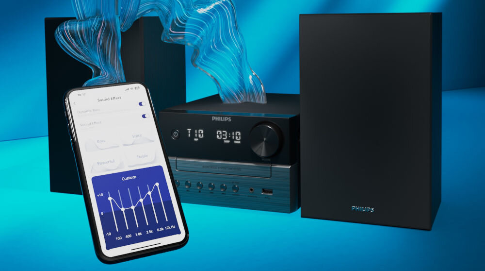 Na obrazie widoczna jest czarna wieża audio z wyświetlaczem pokazującym godzinę 03:10 oraz smartfon z aplikacją do sterowania dźwiękiem. Logo PHILIPS znajduje się na wieży i głośnikach.