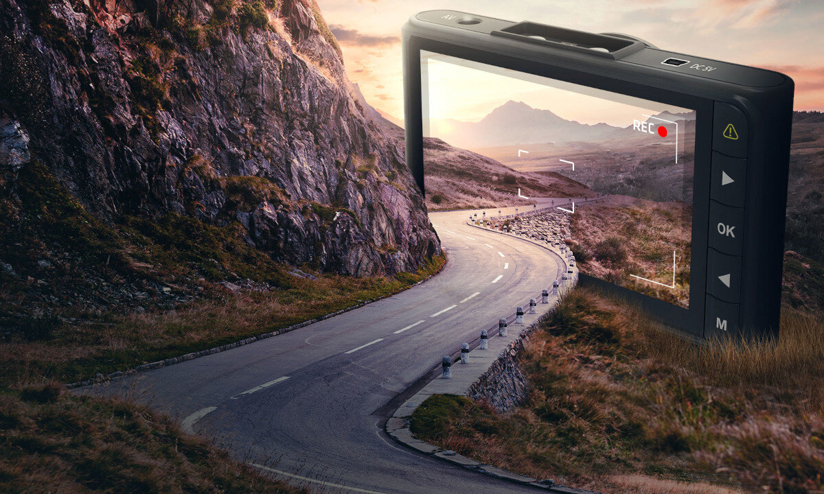 Obraz przedstawia wideorejestrator z widokiem na krętą drogę w górskim krajobrazie. Na ekranie urządzenia widoczny jest symbol nagrywania \'REC\'.