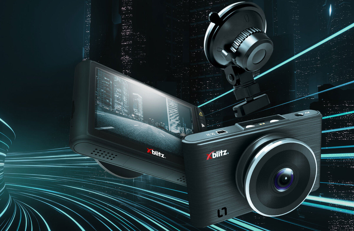 Na obrazie widoczny jest wideorejestrator z logo \'xblitz\', z dużym obiektywem i ekranem wyświetlającym obraz miasta nocą. W tle widać dynamiczne linie świetlne i zarys wieżowców.
