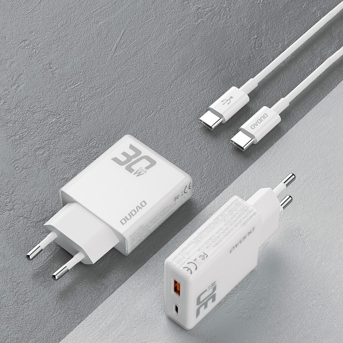 Na obrazie widoczna jest biała ładowarka sieciowa z napisem \'30W GAN\' oraz dwa białe kable USB-C. Na ładowarce znajduje się również logo \'DUDAO\'.