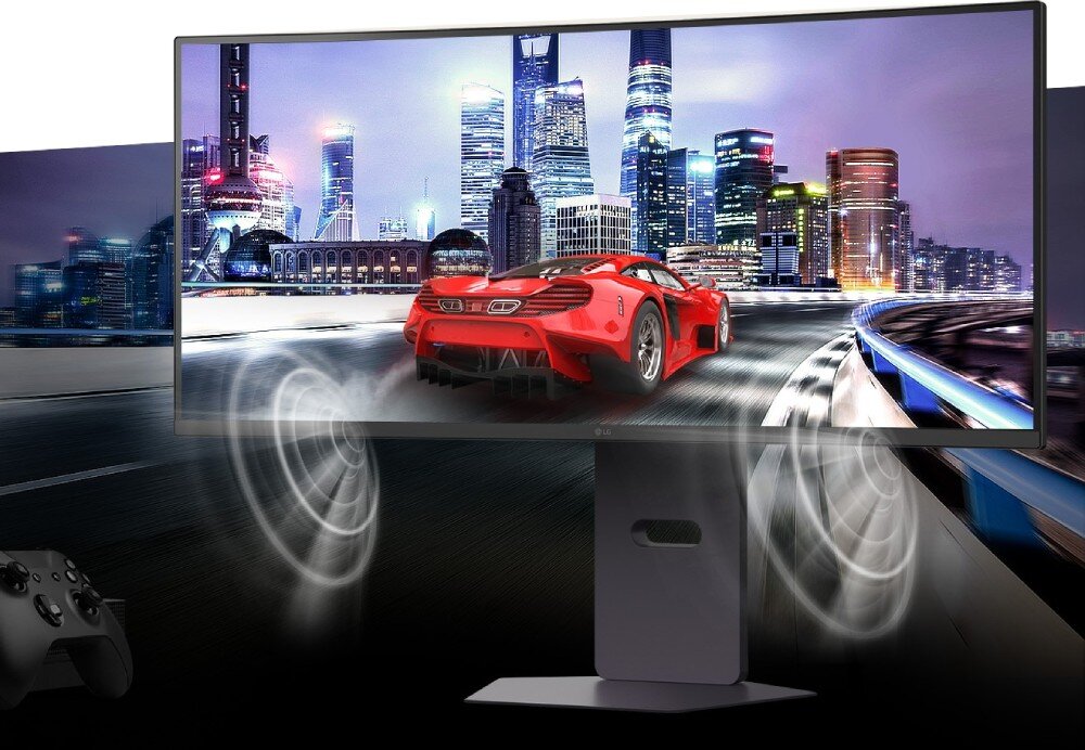Monitor LG UltraGear 34G600A-B Ujęcie monitora na biurku z kontrolerem gier i wizualizacją dźwięku stereo w postaci białych fal przy dolnej krawędzi, ramka, dźwięk, głośniki