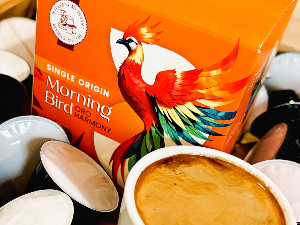 Kapsułki MORNING BIRD Oro Harmony 10 szt. 5 opakowań kawy kapsułkowej a obok opakowanie kawy ziarnistej