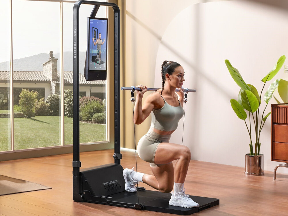 Atlas SPEEDIANCE Gym Monster 2.0 Works Plus pomieszczenie pokój osoba wykonuje ćwiczenia przy atlasie klęczy na jedno kolano domowa siłownia sport zdrowie hobby