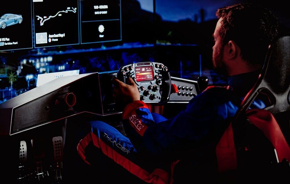 Baza kierownicy MOZA Racing R12 V2 RS081 mężczyzna grający na symulatorze kierownica podłączona do bazy oprogramowanie Pit House zarządzanie parametrami przejrzysty interfejs aplikacja mobilna komfort obsługi