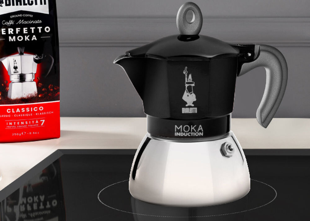 Na obrazie znajduje się czarna kawiarka z napisem \'MOKA INDUCTION\' oraz opakowanie kawy z napisem \'PERFETTO MOKA CLASSICO INTENSITA 7\'.