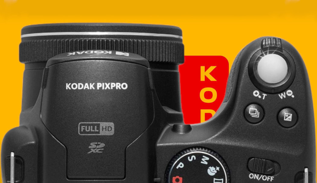 Na obrazie widoczny jest czarny aparat fotograficzny z napisem \'KODAK PIXPRO\' oraz oznaczeniami \'FULL HD\' i \'SDXC\'. W tle znajduje się żółte tło z czerwonym elementem z napisem \'KODAK\'.