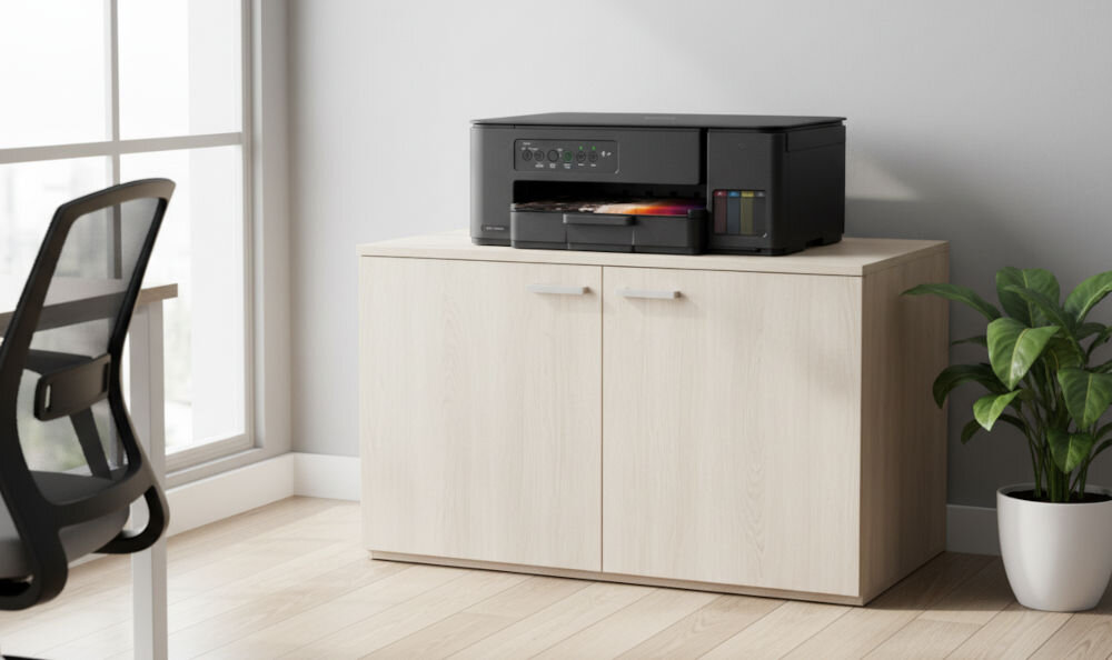 Urządzenie wielofunkcyjne BROTHER DCPT435WYJ1 Druk w kolorze, Wi-Fi prezentacja urządzenia w jasnym pokoju na jasnej szafce obok duże wysokie okno