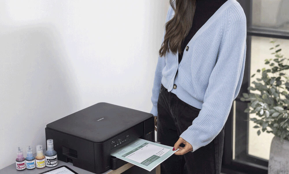 Urządzenie wielofunkcyjne BROTHER DCPT435WYJ1 Druk w kolorze, Wi-Fi kobieta stojąca przy urządzeniu i wyciągająca kartkę z urządzenia w pomieszczeniu rozdzielczość skanowania w kolorze dokumenty zdjęcia rozdzielczość interpolowana wysoka jakość