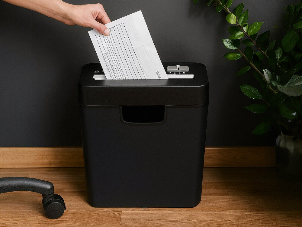 Niszczarka EXTRALINK EX.29836, niszczenie, dokumenty, bezpieczeństwo, prywatność, dłoń wkłada papier A4 do niszczarki stojącek w pokoju