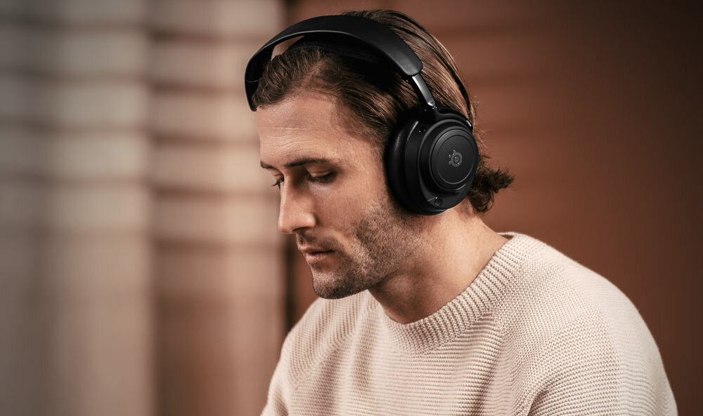 Słuchawki STEELSERIES Arctis Nova Elite ANC mikrofony hybrydowe Transparency mode, osoba z założonymi słuchawkami nausznymi
