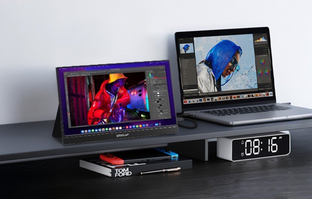 Monitor ZEUSLAP ZP156K Monitor obok laptopa pokazujący program graficzny z kolorową postacią, na biurku stoi zegar elektroniczny i konsola przenośna, przekątna, rozdzielczość