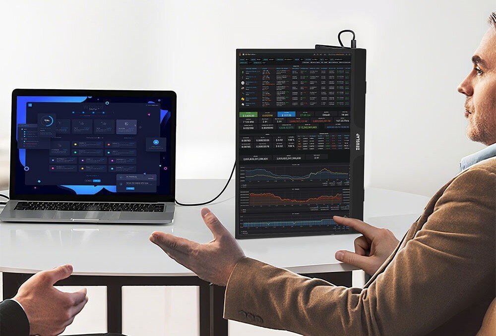 Monitor ZEUSLAP Z15ST Mężczyzna siedzący przy stole patrzy na laptopa i dodatkowy monitor ustawiony pionowo z wykresami i tabelami, opis