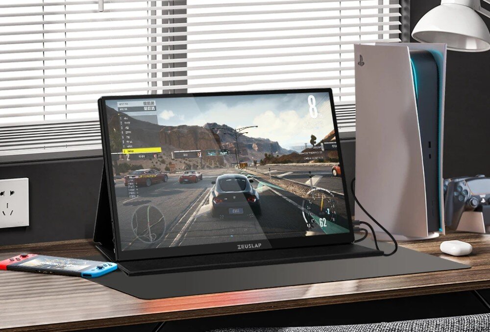 Monitor ZEUSLAP P16KT Monitor przenośny stojący na biurku, wyświetlający wyścig samochodowy, obok konsola i kontroler oraz konsola przenośna leżąca na blacie, opis