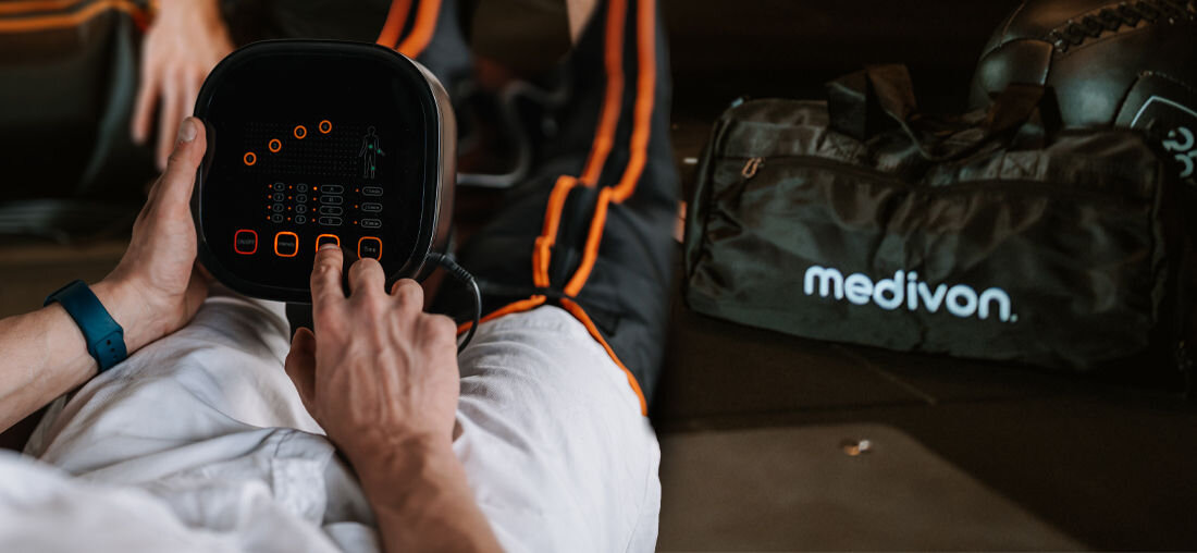 Osoba trzyma panel sterujący z wyświetlaczem i przyciskami, obok widoczna torba z napisem \'medivon\'.