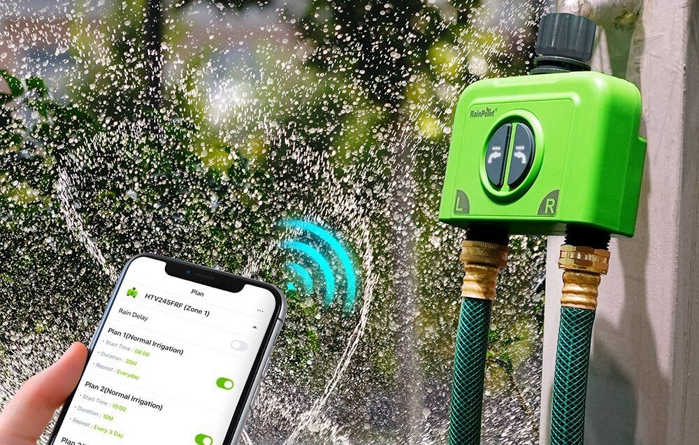 Na obrazie widoczny jest zielony sterownik nawadniania z logo \'RainPoint\', do którego podłączone są dwa węże ogrodowe. Obok znajduje się smartfon z aplikacją pokazującą plan nawadniania \'HTV245FRF (Zone 1)\'.